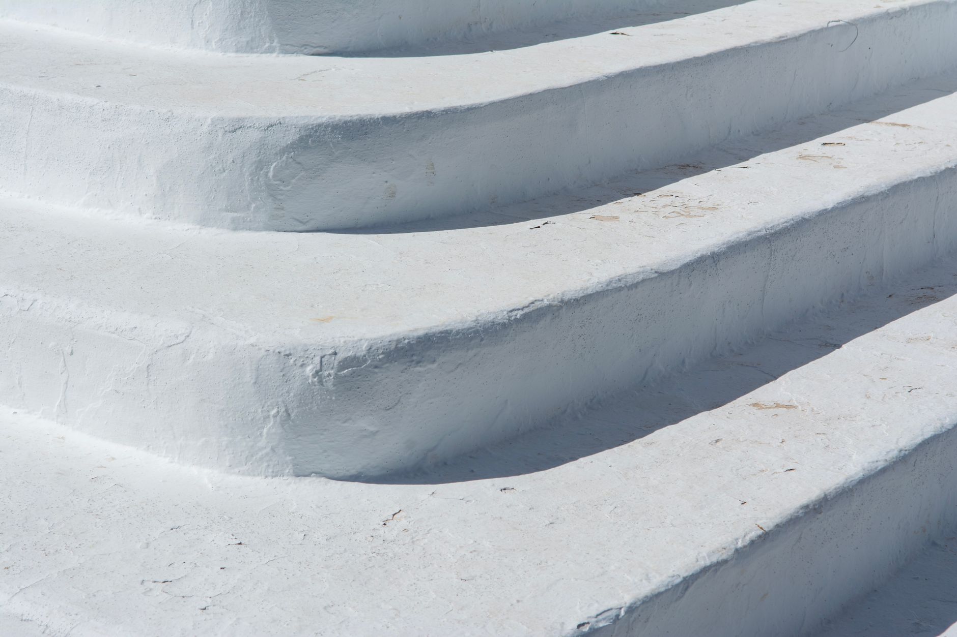 Close-up of textured white concrete steps in bright sunlight, showcasing minimalist design in Carlsbad, CA