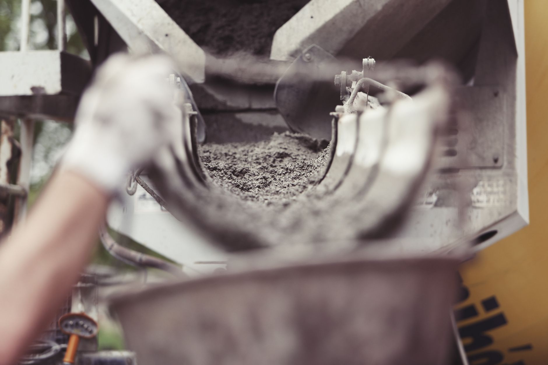 Close-up of concrete being poured from a mixer truck at a construction site with a worker's hand visible in Carlsbad, CA